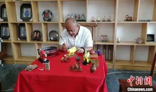 29日，山西省长治市黎城县一间工作室内，46岁的张学义手拿画笔，细致地刻画老虎造型。黎城县融媒体中心供图