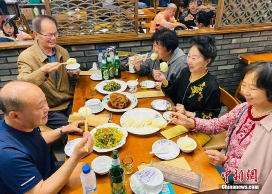图为6月1日，食客在餐馆品尝“雪衣豆沙”。 中新社发 李丹 摄