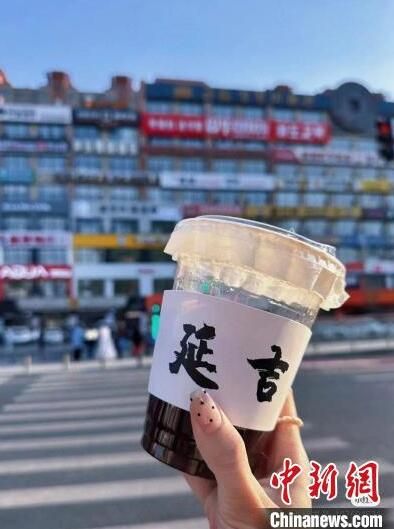 游客拿着咖啡到延吉“网红墙”前打卡。 延吉市委宣传部供图 游客拿着咖啡到延吉“网红墙”前打卡。 延吉市委宣传部供图